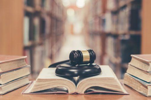A book sits open on a table in a library with a gavel laying across it.