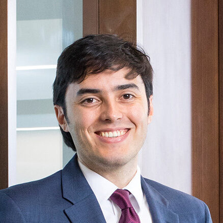 Smiling man in a suit with red tie.