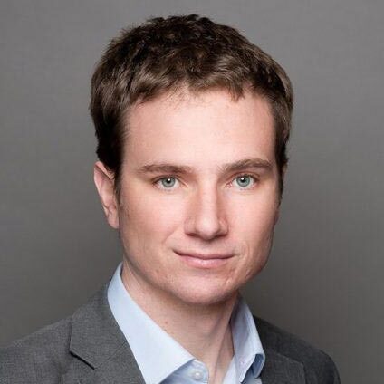 Man with short brown hair and blue shirt. Headshot.