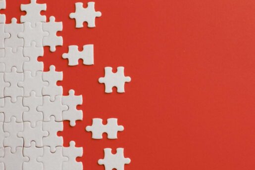 White puzzle pieces being put together with a red background