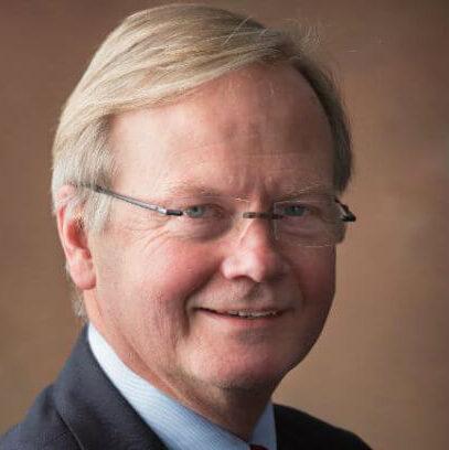 Older man in suite with glasses and golden hair.