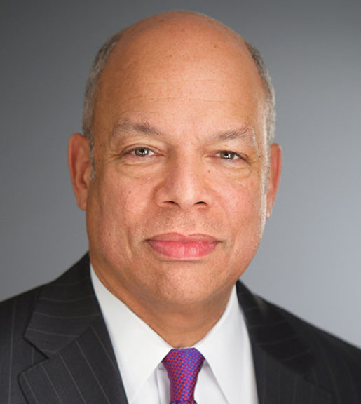 A Black man wearing a suit and tie looks directly at the camera.