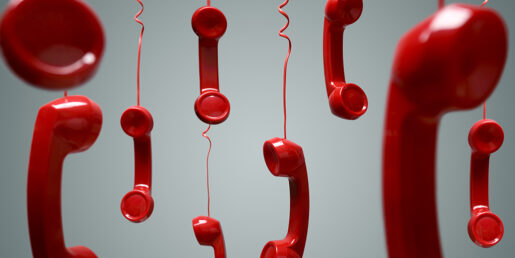Image of hanging red telephones by their cords.