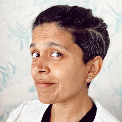 A headshot of a South Asian individual with close cropped hair.