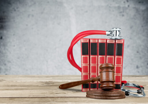 A stethoscope sits on a set of red books with a gavel in front of them.
