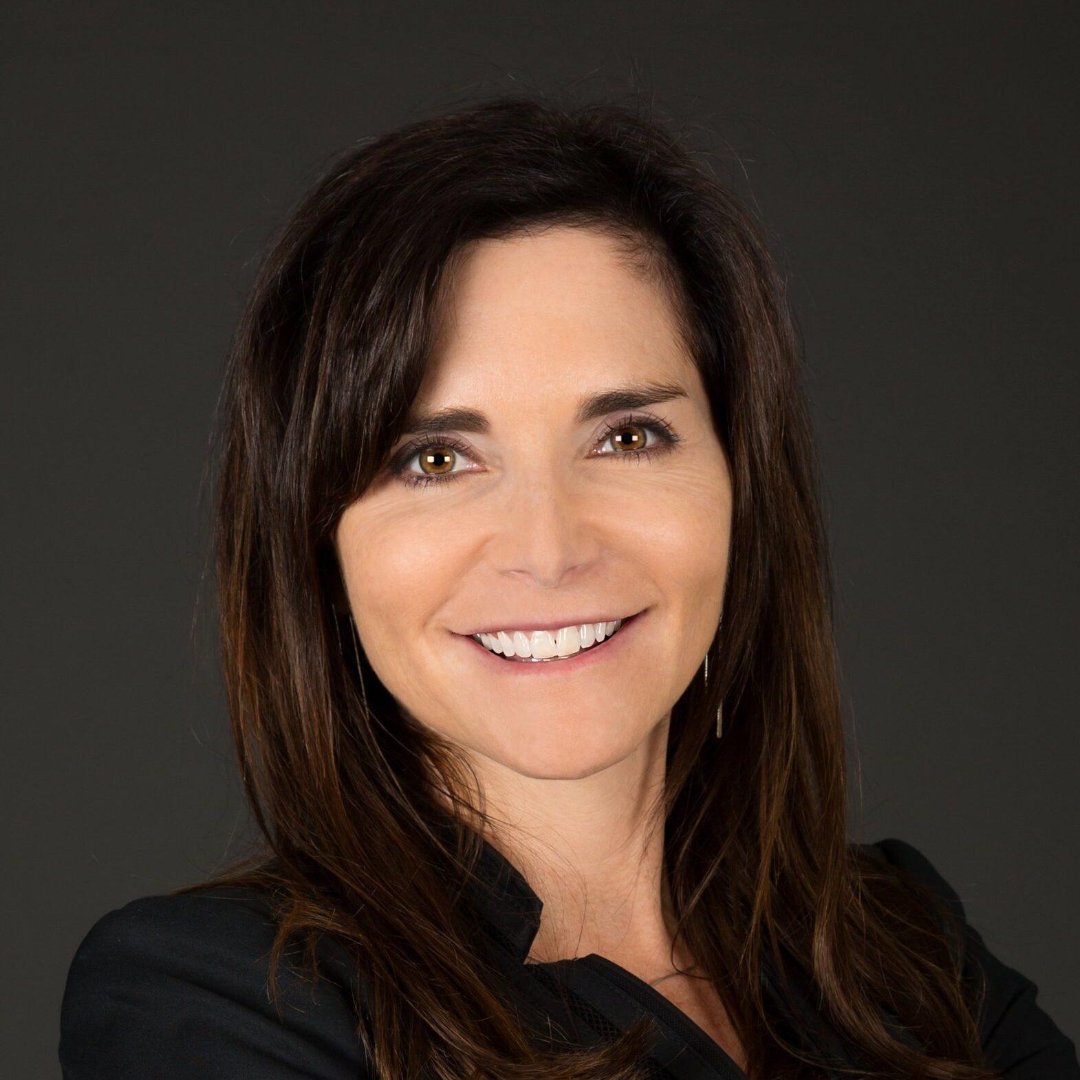 Woman with brown hair smiles broadly.