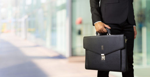 A businessman wearing a crisp suit holds a briefcase.