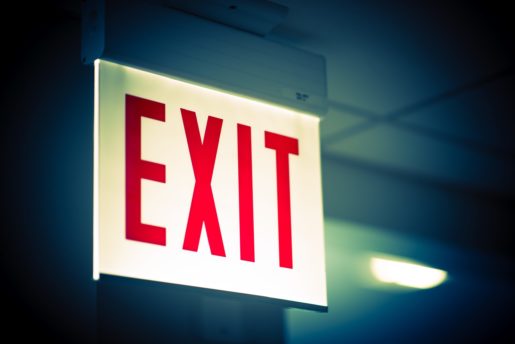 An illuminated exit sign hangs in a corporate office.