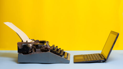 A typewriter and a computer face off against a yellow background.