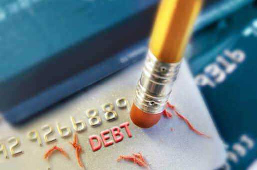A pencil erases the word debt off a credit card.