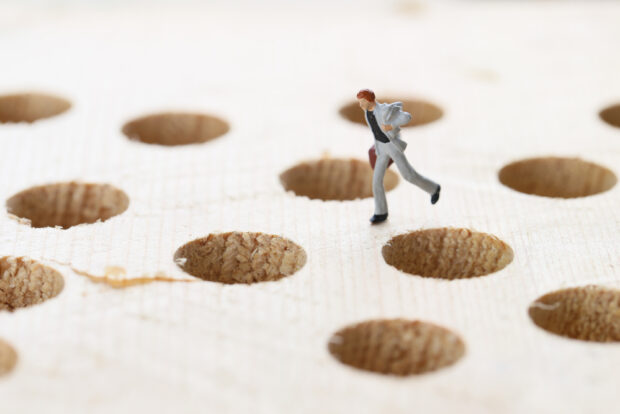 A man jumps around trying to avoid holes.