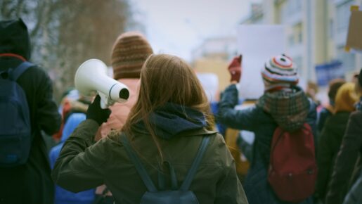 Individuals march and hold signs in protest.