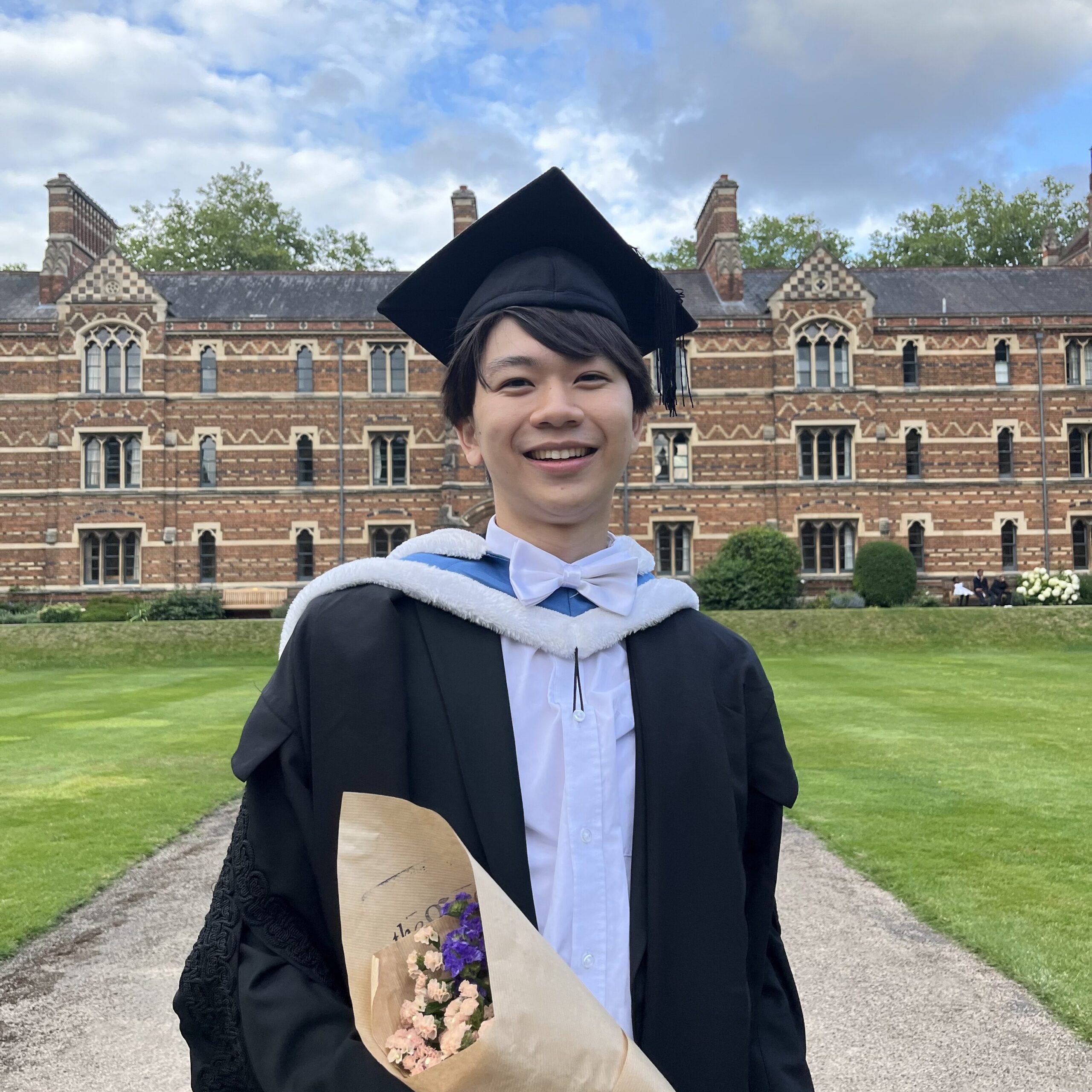 Headshot of David Wong, holding flowers and wearing a graduation cap and gown.