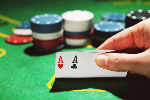 A hand lifts up two aces playing poker.