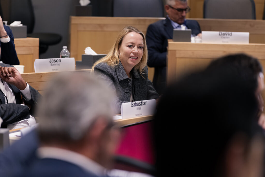 A woman smiles and speaks in a classroom.
