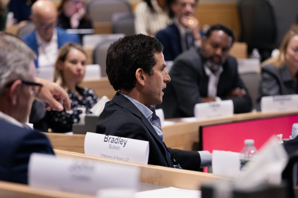 A man speaks in a classroom while others listen.